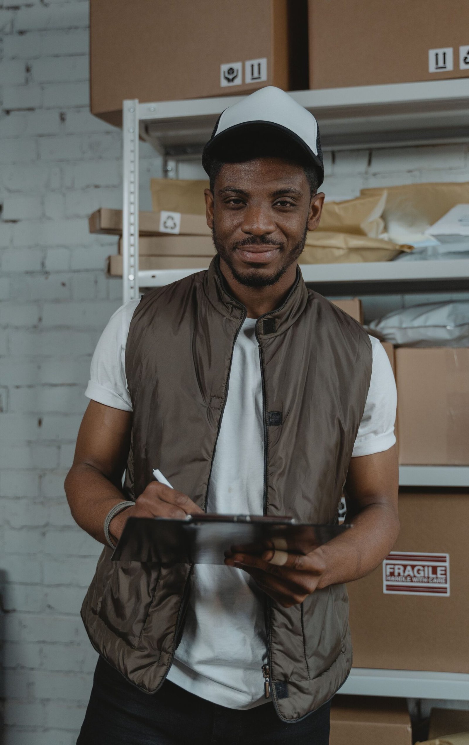 Smiling warehouse worker with a clipboard in front of shelves